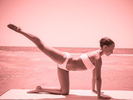 Woman doing yoga asana at the beach