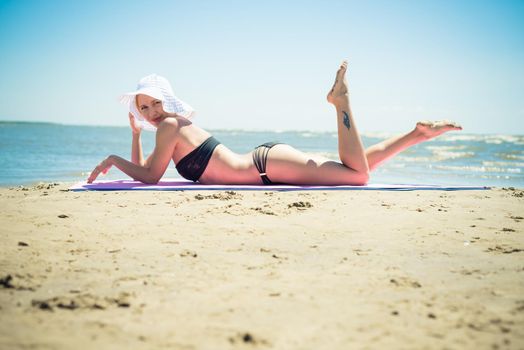 Beautiful red woman wearing bikini standing on the beach enjoying the sun