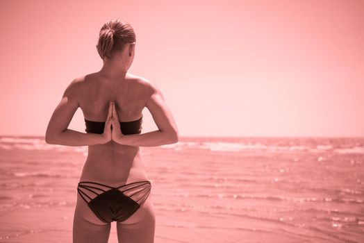 Woman doing yoga asana reverse namaste at the beach