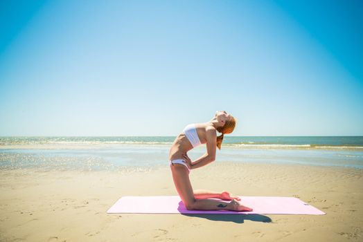 Woman doing yoga asana at the beach