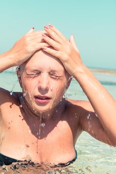 Young woman washing her face in the sea