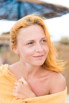 Beautiful woman sitting wrapped in towel on the beach