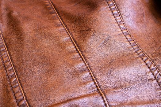 Seams on a brown leather product closeup, abstract background