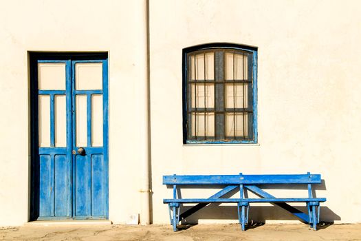 Typical Andalusian whitewashed facade with blue painted window and bench