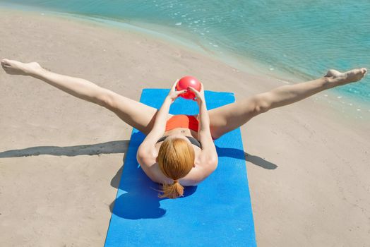 Young woman doing fitness yoga at the beach