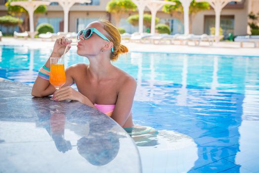 Girl in pool bar at tropical tourist resort vacation destination