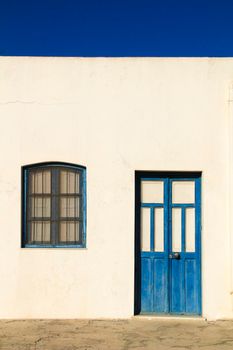 Typical Andalusian whitewashed facade with blue painted window and bench