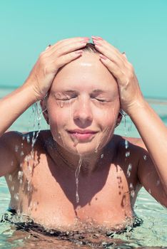 Young woman washing her face in the sea