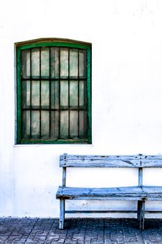 Typical Andalusian whitewashed facade with blue painted window and bench