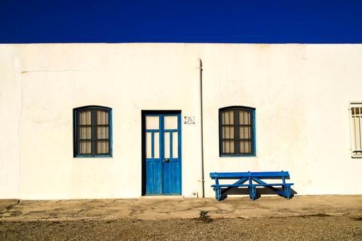 Typical Andalusian whitewashed facade with blue painted window and bench