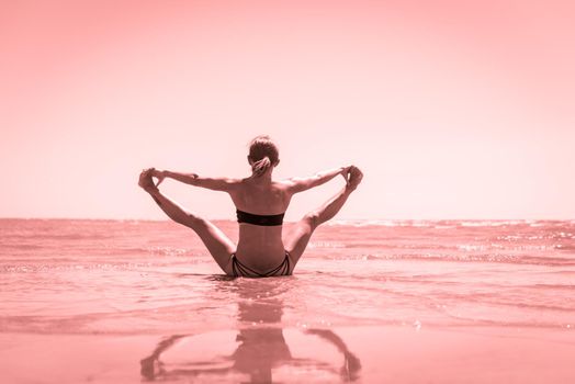 Woman doing yoga asana at the beach