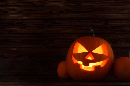 Halloween pumpkin with cut face and candle inside dark holiday card