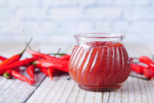 chili and tomato sauce in a small jar on table ,