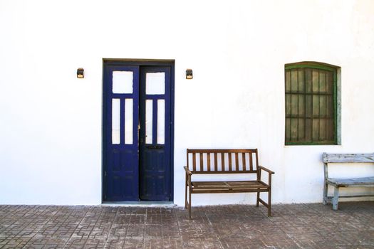 Typical Andalusian whitewashed facade with blue painted window and bench