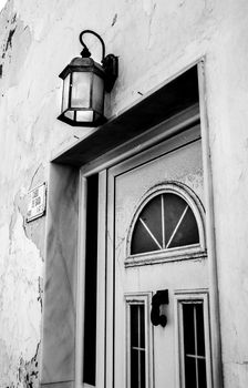 Typical Andalusian whitewashed facade with white metal door and vintage lantern