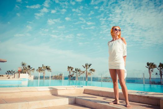 Young woman enjoying sun by pool at tourist resort