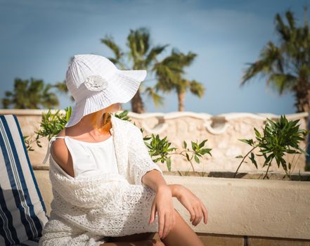 Young woman enjoying sun on sunbed at tourist resort