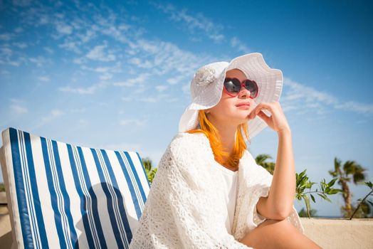 Young woman enjoying sun on sunbed at tourist resort