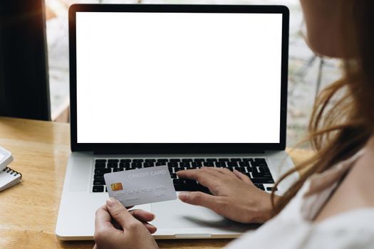 Woman holding credit card and using laptop computer while shopping online. Blank screen for your advertising