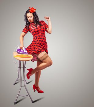 young beautiful brunette woman ironing her dress with iron. pin-up style