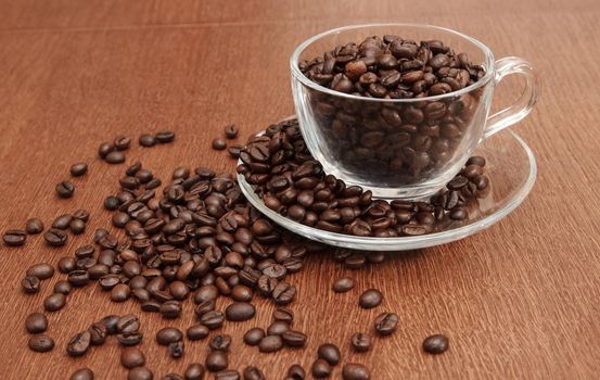 coffee beans in a cup on wooden table. indoor closeup