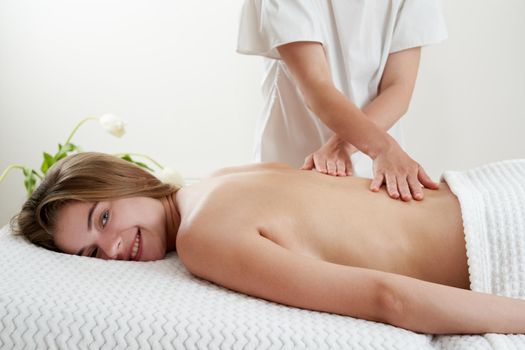 Masseur massaging young woman on massage table in a spa salon. Young woman relaxing during back massage at the spa. Spa treatment concept