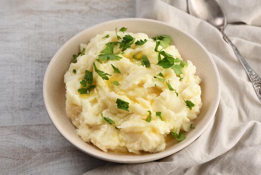 A plate of mashed potatoes poured with melted butter and seasoned with greens