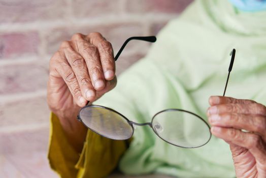 Close up of senior women hand holding old eyeglass.