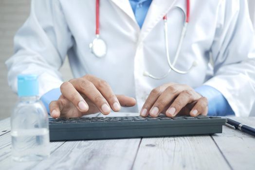 young male doctor typing on keyboard on desk