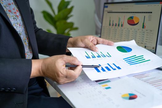 Asian accountant working and analyzing financial reports project accounting with chart graph and calculator in modern office, finance and business concept.