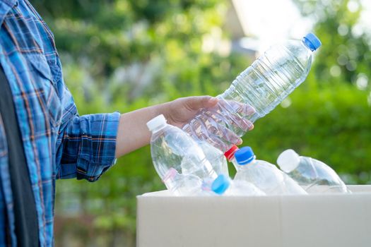 Asian woman volunteer carry water plastic bottles into garbage box trash in park, recycle waste environment ecology concept.