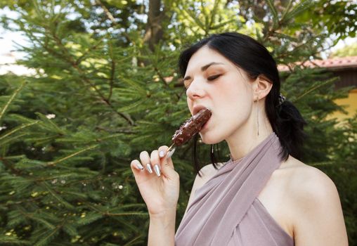 young brunette woman eating ice cream outdoor on summer day