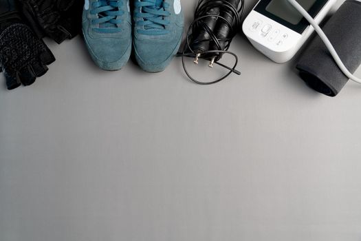 Healthy lifestyle. Jump rope  equipment and sphygmomanometer on a grey background. Top view with copy space.