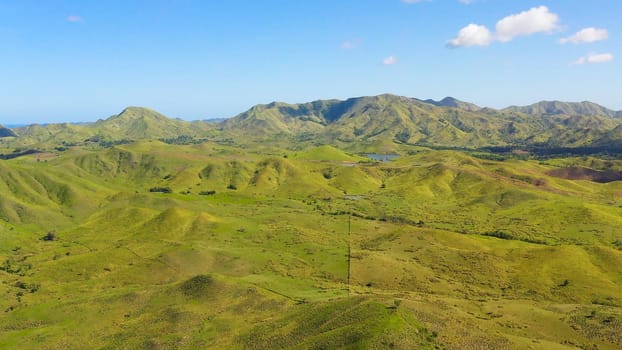 Hills and mountains covered with green grass against a background of blue sky and clouds. Bohol, Philippines. Summer landscape.