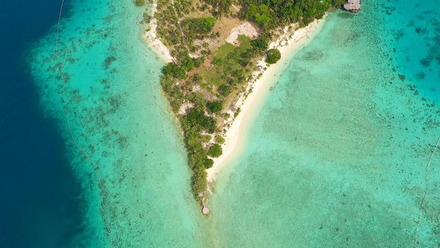 Top view of small tropical island in the blue sea with a coral reef and the beach. Malipano island, Philippines, Samal.