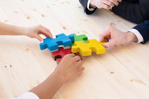 Business people team assembling four color jigsaw puzzle pieces unity cooperation ideas concept