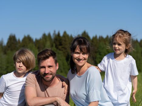 Happy smiling family: man, woman and kids having fun outdoors against blue sky background. Summer vacations concept