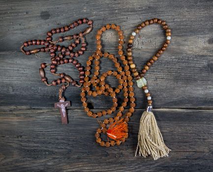 group of rosaries of different religions on rustic wood