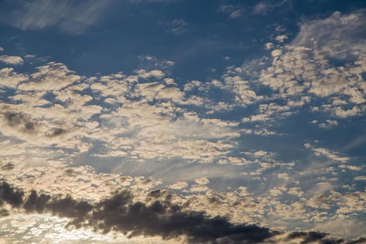 Beautiful blue sky with white cirrus, fluffy clouds at sunset. Sky panorama for screensavers, postcards, calendar, presentations. Low point at wide angle. Warm spring or summer evening.