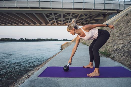 Woman exercising kettlebell pilates outdoor.