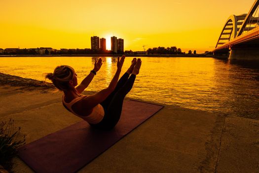 Woman exercising pilates on sunny day. Teaser exercise.