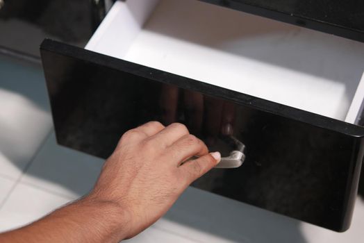 man's hand open drawer wooden in cabinet.