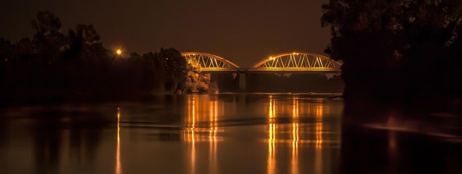 Bridge over the river illuminated at night, banner image with copy space