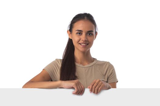 Casual latin woman with a banner isolated over a white background