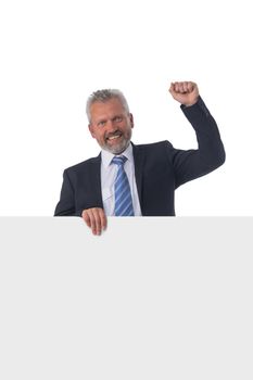 Smiling mature businessman holding a white panel and gesturing isolated on white background