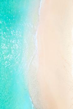 A view from a height of a Tropical beach and waves breaking on a tropical golden sandy beach. The sea waves gently wind along the beautiful sandy beach.