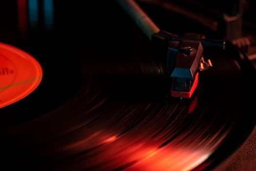 Needle detail on vinyl record on turntable, low light image with reflection