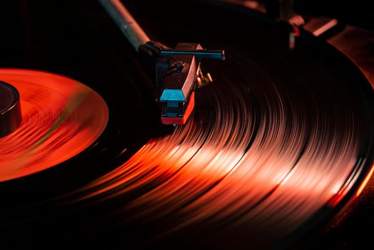 Needle detail on vinyl record on turntable, low light image with reflection