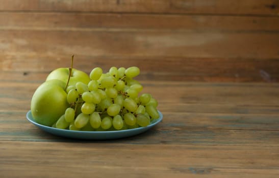 Plate of delicious fresh fruits like  apples and grapes on a table