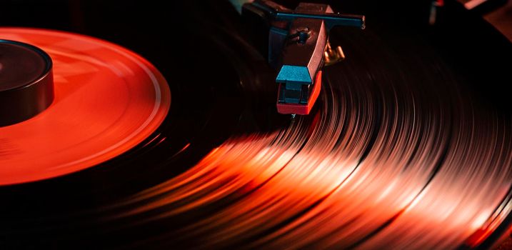 Needle detail on vinyl record on turntable, low light image with reflection